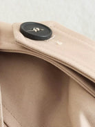 Beigefarbener Trenchcoat-Kragen mit schwarzem Knopf, elegantes Design, hochwertige Verarbeitung, zeitloser Modestil, klassischer Look.
