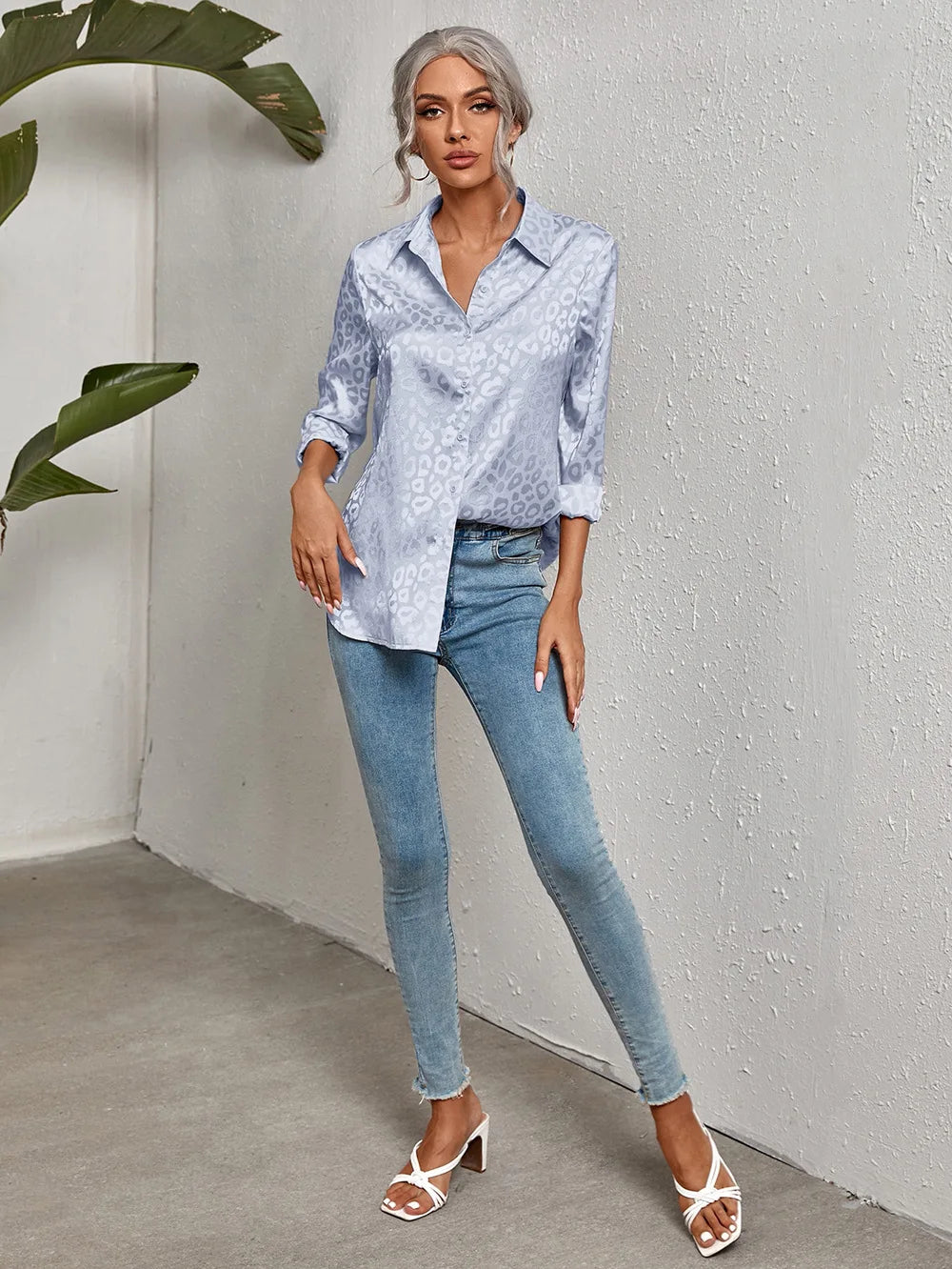 Damenmode: Elegante, hellblaue Bluse mit Leopardenmuster, kombiniert mit engen Jeans und weißen Sandaletten. Perfekt für den Casual-Chic-Look.