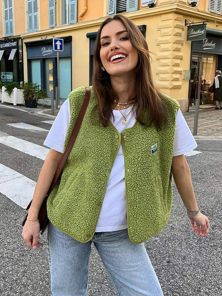 Frau trägt grüne Fleeceweste über weißem T-Shirt, lächelnd auf Straße. Modetrend, lässiger Stil, Herbstmode, Damenbekleidung, urbaner Look.