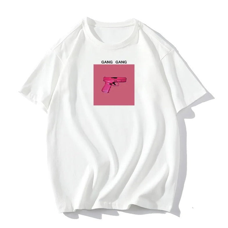Weißes T-Shirt mit pinkem Pistolen-Print und "GANG GANG"-Schriftzug. Trendige Streetwear, Unisex, Baumwolle, lässiger Stil, modisches Design.