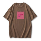 Braunes T-Shirt mit pinkem Pistolen-Print und "Gang Gang"-Schriftzug. Trendige Streetwear, lässiger Stil, Unisex-Mode, Baumwolle.