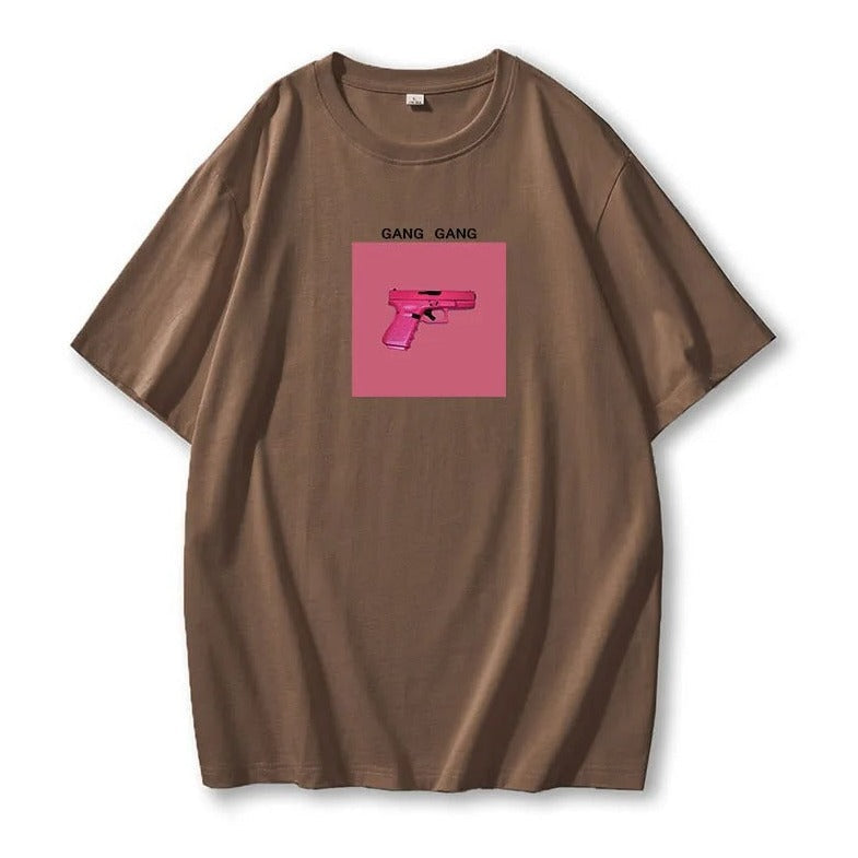 Braunes T-Shirt mit pinkem Pistolen-Print und "Gang Gang"-Schriftzug. Trendige Streetwear, lässiger Stil, Unisex-Mode, Baumwolle.