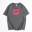 Graues T-Shirt mit pinkem Pistolen-Print und "Gang Gang"-Schriftzug. Trendige Streetwear, ideal für urbane Mode und lässigen Stil.