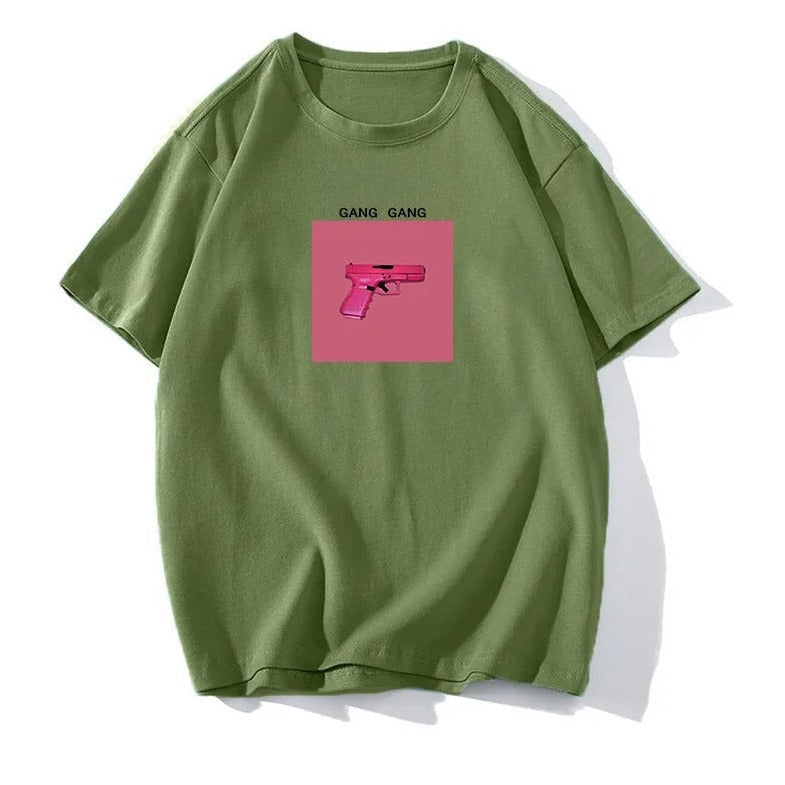 Grünes T-Shirt mit pinkem Pistolen-Print und "Gang Gang"-Schriftzug. Trendige Streetwear, lässiger Stil, hochwertiger Baumwollstoff.