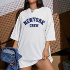 Weißes Oversize-T-Shirt mit "New York Crew"-Aufdruck, lässiger Streetwear-Stil, ideal für trendige Mode, Damenmode, urbaner Look.