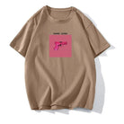 Beiges T-Shirt mit pinkem Pistolen-Print und "Gang Gang"-Schriftzug. Trendige Streetwear, lässiger Stil, ideal für urbane Modefans.
