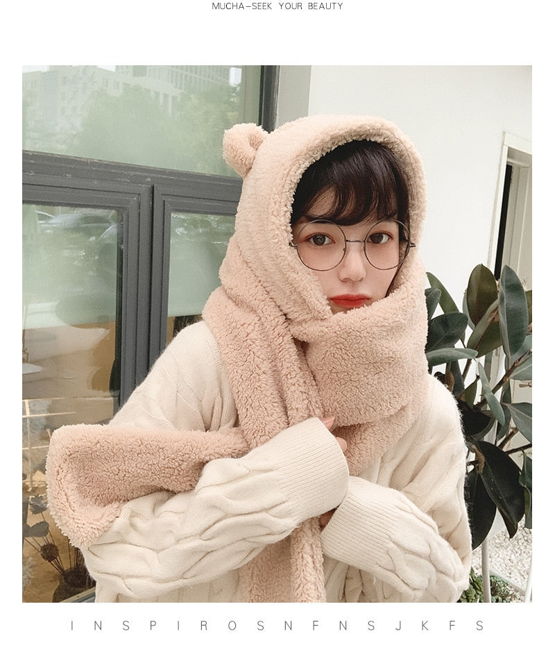 Frau mit Brille trägt flauschigen, beigen Schal mit Kapuze und Bärenohren. Modetrend, Winteraccessoire, gemütlicher Look, stilvoller Schutz.