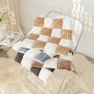 Patchwork-Decke aus Plüsch in Beige, Weiß und Grau auf Stuhl, gemütliche Wohnkultur.