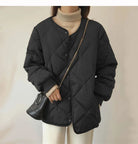 Schwarze gesteppte Damenjacke mit Knopfleiste, kombiniert mit beigem Rollkragenpullover und kleiner schwarzer Umhängetasche. Wintermode-Trend.