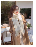 Frau in elegantem, beigem Mantel und weißem Schal, lächelnd im Freien. Modetrend Herbst/Winter, stilvolle Damenbekleidung, Outdoor-Mode.