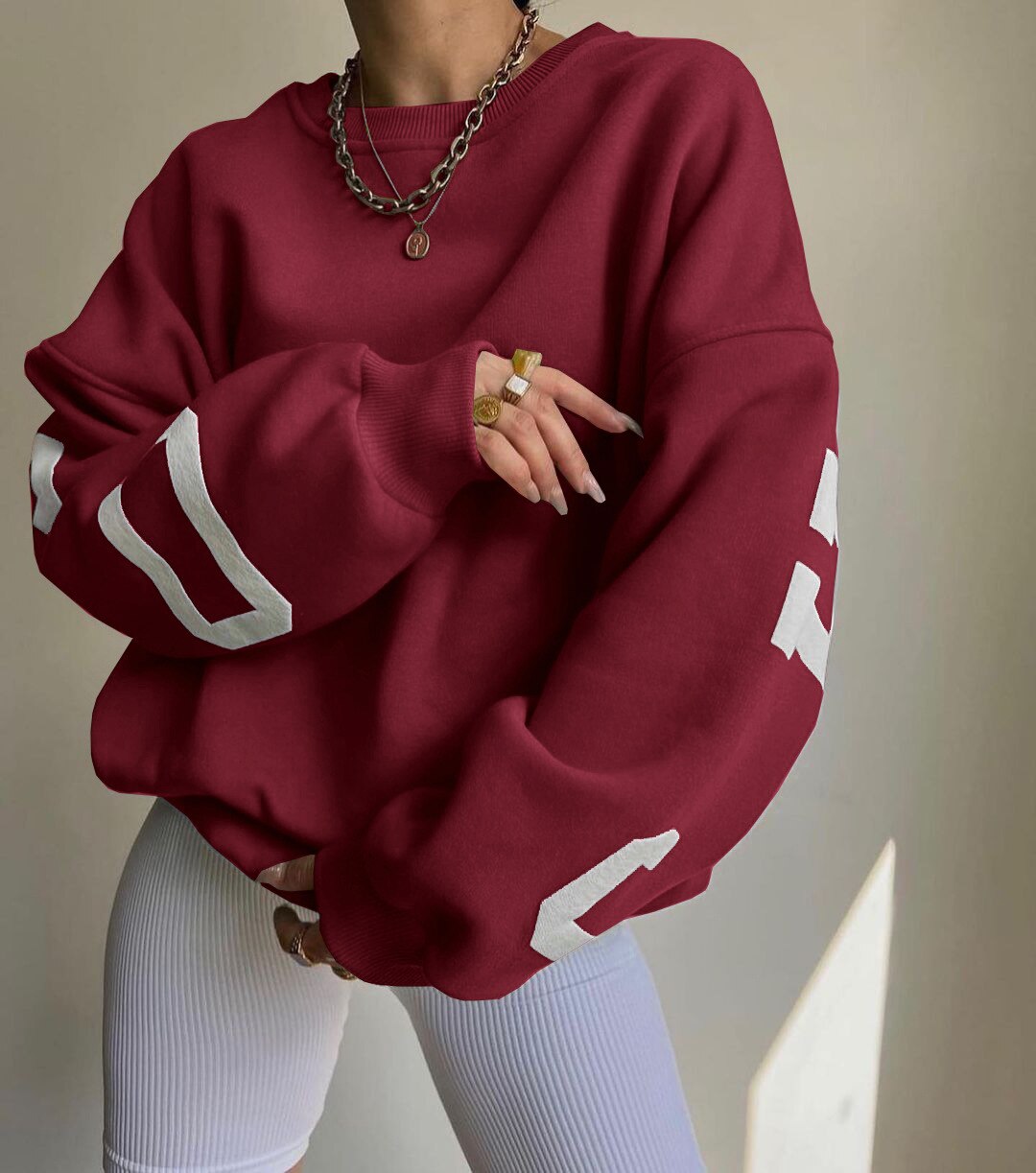 Dunkelroter Oversize-Pullover mit weißen Zahlen, kombiniert mit weißen Leggings. Modetrend, lässiger Stil, bequeme Freizeitkleidung.