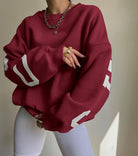 Dunkelroter Oversize-Pullover mit weißen Zahlen, kombiniert mit weißen Leggings. Modetrend, lässiger Stil, bequeme Freizeitkleidung.