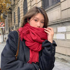 Frau mit rotem Schal und schwarzem Mantel auf städtischer Straße. Herbstmode, stilvoll, warm, elegant. Perfekt für kühle Tage.