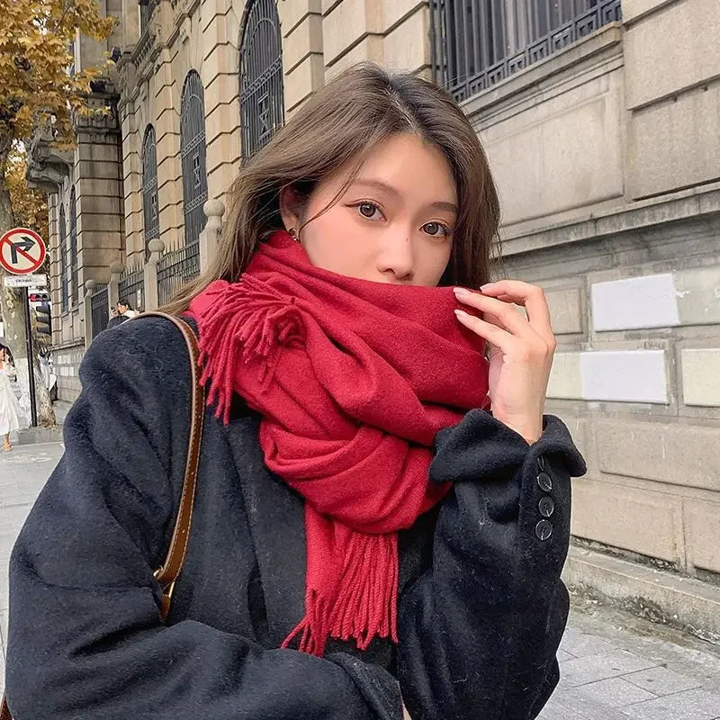 Frau mit rotem Schal und schwarzem Mantel auf städtischer Straße. Herbstmode, stilvoll, warm, elegant. Perfekt für kühle Tage.