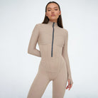 Damen-Einteiler in Beige mit Reißverschluss, figurbetont, langärmelig. Perfekt für Fitness, Yoga und Freizeit. Modisch und bequem.