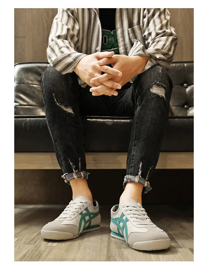 Graue Sneaker mit türkisfarbenem Logo, getragen von einer Person in zerrissenen Jeans. Modische Freizeitschuhe, ideal für urbanen Streetstyle.