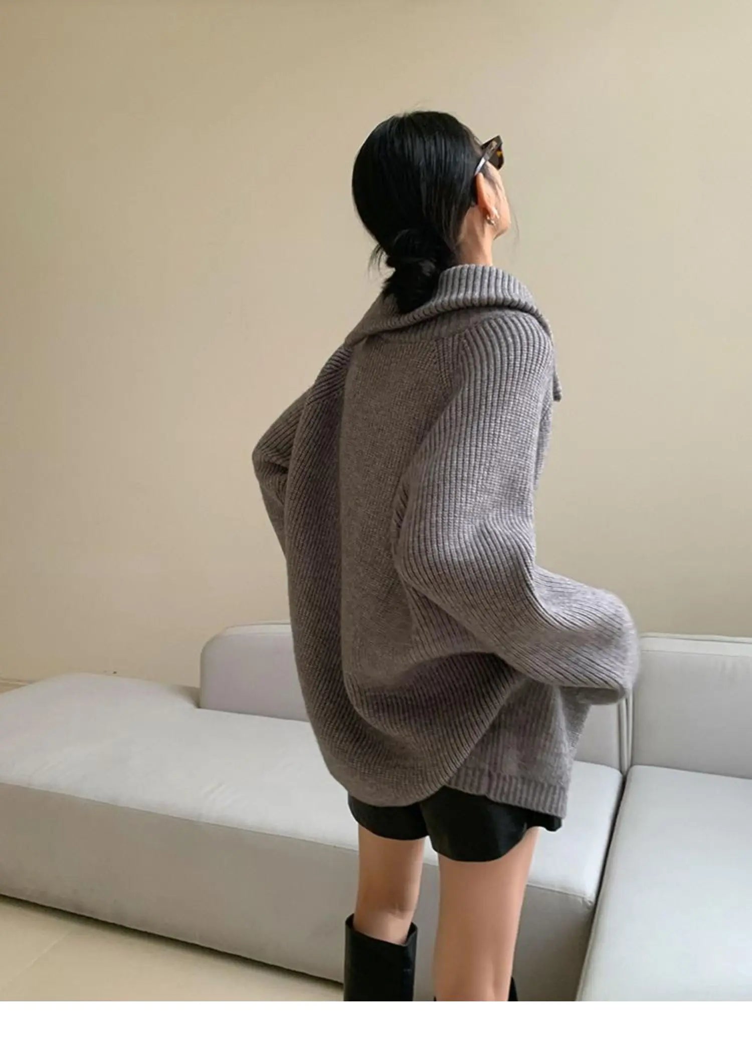 Damenmode: Grauer Oversize-Strickpullover mit Rollkragen, kombiniert mit schwarzer Shorts. Trendiger Herbstlook, gemütlich und stilvoll.
