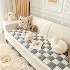 Beige Sofa mit kariertem Überwurf, dekorativen Kissen und Blumen, skandinavisches Wohnzimmer.