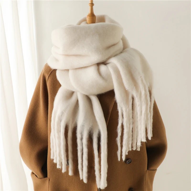 Weicher, weißer Wollschal mit Fransen auf braunem Mantel. Perfekt für Wintermode, warm und stilvoll. Hochwertige Accessoires für kalte Tage.