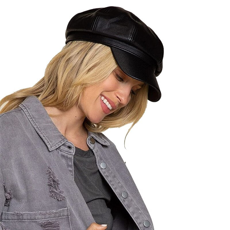 Frau mit schwarzer Leder-Baker-Boy-Mütze und grauer Jacke. Modetrend, stilvolles Accessoire, urbaner Look, Damenmode, Herbstoutfit.