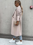 Eleganter Damenmantel in Beige, kombiniert mit weißen Sneakers und einer stilvollen Handtasche. Perfekt für modische Herbst- und Winteroutfits.