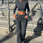 Damen-Sportanzug in Dunkelgrau, langärmeliges Crop-Top und weite Hose, ideal für Fitness und Freizeit. Modisch, bequem, atmungsaktiv.