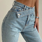Damen-High-Waist-Jeans in hellblauer Waschung, modisch mit asymmetrischem Knopfverschluss. Perfekt für trendige Streetwear-Looks.
