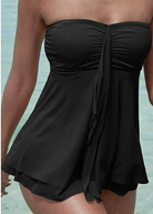 Frau in schwarzem Badeanzug am Strand, trägerlos, elegantes Design, Sommermode.