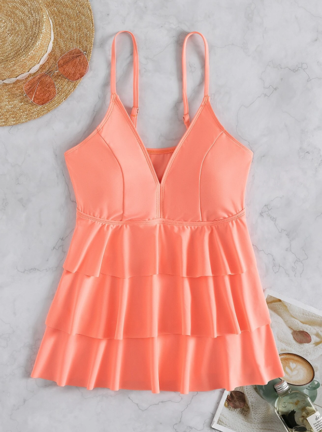 Ärmelloses, pfirsichfarbenes Sommerkleid mit V-Ausschnitt und Rüschen auf Marmorhintergrund, ideal für Strandmode und Sommeroutfits.