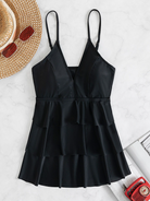 Schwarzes, ärmelloses Sommerkleid mit V-Ausschnitt und Rüschen, ideal für Strandmode. Perfekt kombiniert mit Strohhut und Sonnenbrille.