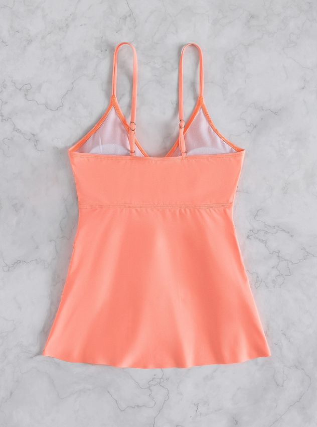 Pfirsichfarbenes Damen-Top mit verstellbaren Trägern auf Marmorhintergrund. Sommermode, elegantes Design, atmungsaktiver Stoff.