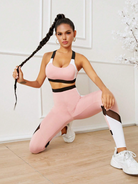 Frau in rosa Sportbekleidung, kniend auf Holzboden, mit langen Zöpfen. Fitnessmode, athletische Kleidung, trendige Sportoutfits.