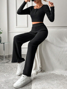 Damen-Outfit in Schwarz: Langarm-Crop-Top und weite Hose, kombiniert mit weißen Sneakers. Stilvolle Mode für Freizeit und Streetwear.