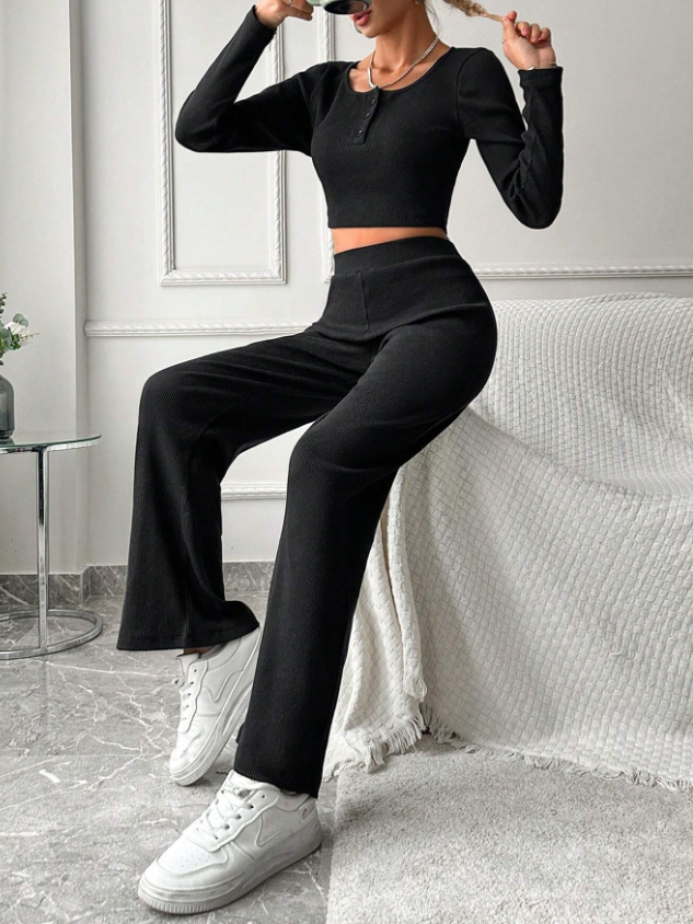 Damen-Outfit in Schwarz: Langarm-Crop-Top und weite Hose, kombiniert mit weißen Sneakers. Stilvolle Mode für Freizeit und Streetwear.