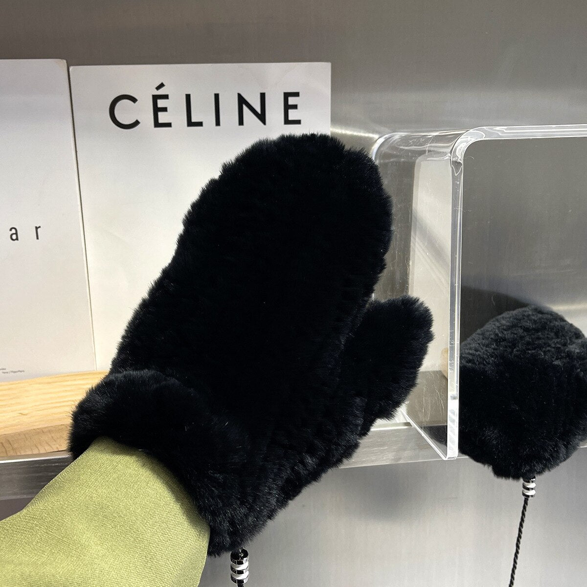 Schwarzer Pelzhandschuh auf Bücherregal, stilvoll und warm, ideal für Wintermode. Luxuriöses Accessoire, perfekt für kalte Tage.