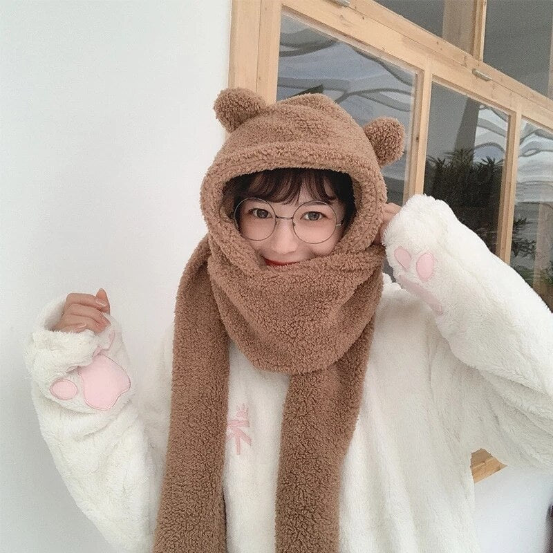 Frau in flauschigem Bärenkostüm mit Kapuze und Schal, trägt Brille. Perfekt für kalte Tage, modisch und gemütlich. Wintermode, Damenbekleidung.