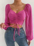 Damenmode: Pinkes, gerafftes Crop-Top mit langen, transparenten Ärmeln. Perfekt für trendige Outfits. Ideal für Frühling und Sommer.