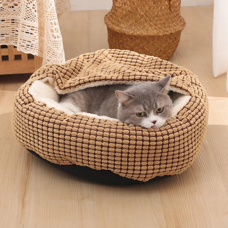 Graue Katze in braunem, weichem Katzenbett aus Plüsch auf Holzboden, gemütlich und entspannt.