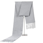 Grauer Kaschmirschal mit Fransen, luxuriös und weich, ideal für kalte Wintertage. Hochwertige Modeaccessoires, stilvoll und zeitlos.