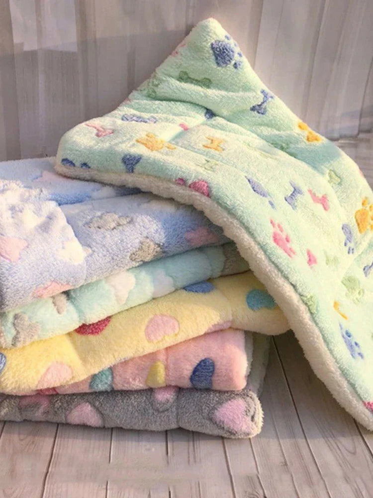 Weiche Babydecken aus Fleece, bunt gemustert, gestapelt auf Holzboden.