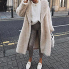 Eleganter Damen-Look mit langem, flauschigem Kunstpelzmantel, weißem Pullover und modischen Schlangenleder-Leggings. Perfekt für den Winter.