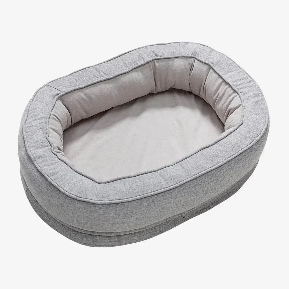 Graues ovales Hundebett aus Stoff, gemütlich und waschbar, ideal für kleine Hunde.