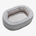 Graues ovales Hundebett aus Stoff, gemütlich und waschbar, ideal für kleine Hunde.