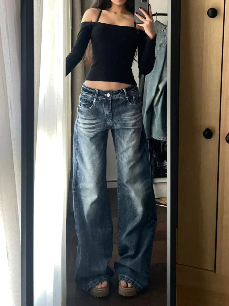 Frau in weitem Jeans und schwarzem Off-Shoulder-Top, Spiegel-Selfie. Trendige Damenmode, lässiger Streetstyle, modische Outfits.