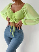 Damenmode: Trendiges, limettengrünes Crop-Top mit Puffärmeln und Raffung, kombiniert mit figurbetonter Jeans. Perfekt für stilvolle Freizeitlooks.