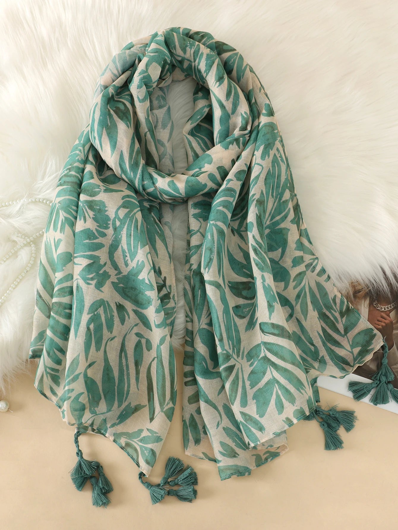 Grüner Blätterschal mit Quasten, weiches Material, modisches Accessoire, ideal für Herbst und Winter, Damenmode, elegantes Design.