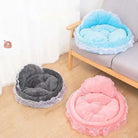 Herzförmige Haustierbetten in Blau, Grau und Rosa mit Rüschen, auf Holzboden neben Sofa.