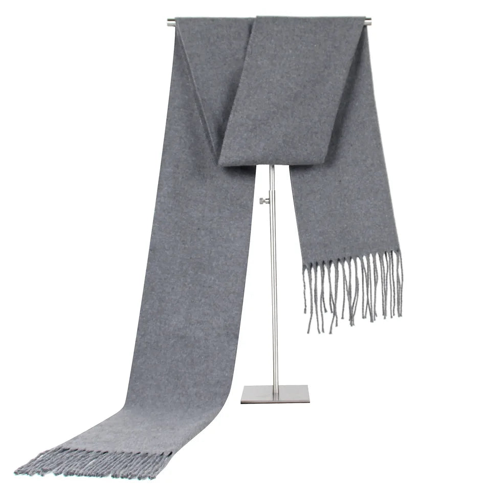 Grauer Wollschal mit Fransen, elegant und warm, ideal für Herbst und Winter. Hochwertige Materialien, zeitloses Design, vielseitig kombinierbar.