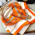 Luxuriöses Seidentuch mit orangefarbenem Ketten- und Gürtelmuster, ideal als modisches Accessoire. Perfekt für stilvolle Outfits und elegante Looks.