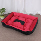 Rotes und schwarzes Hundebett aus Plüsch, rechteckig, mit Knochenmotiv, auf Teppichboden.